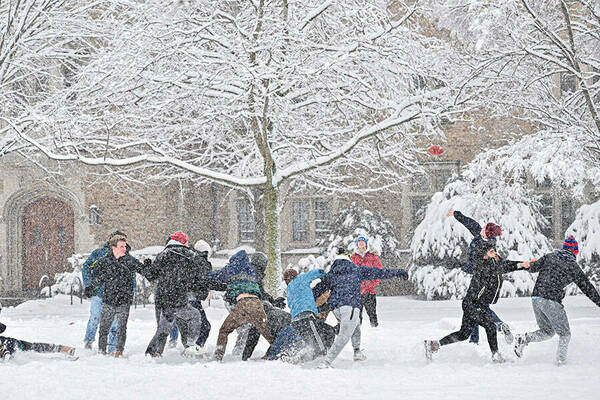 Alumni Hall resident play football on South Quad during a snowstorm.